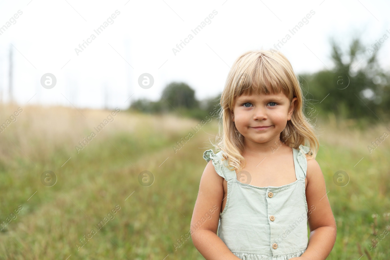 Photo of Portrait of cute little girl at meadow, space for text. Child enjoying beautiful nature