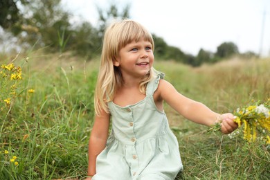 Photo of Cute little girl with flowers at meadow. Child enjoying beautiful nature