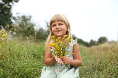 Photo of Cute little girl with flowers at meadow. Child enjoying beautiful nature