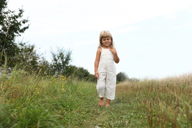 Photo of Cute little girl walking barefoot at meadow. Child enjoying beautiful nature