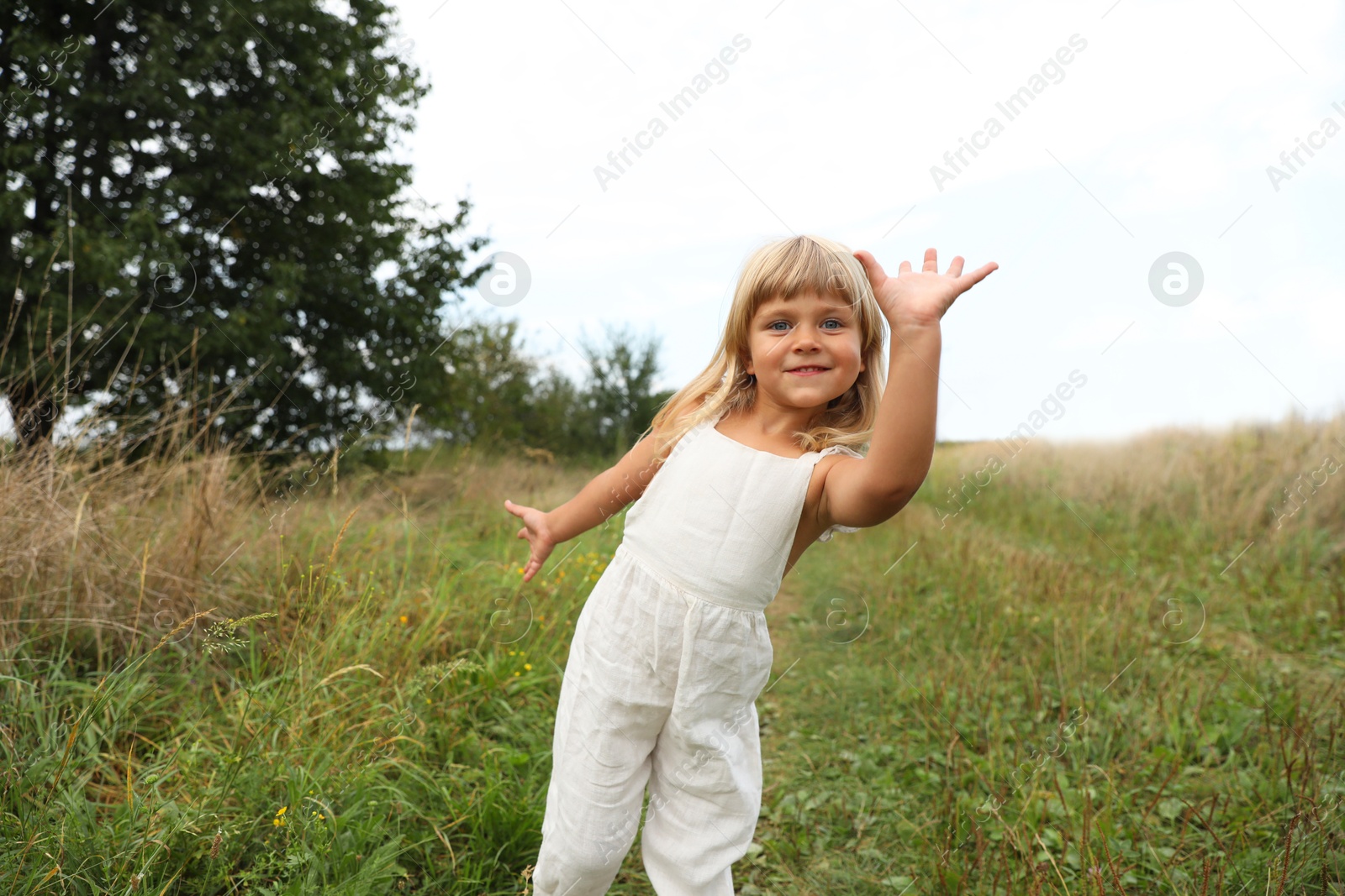 Photo of Cute little girl walking at meadow. Child enjoying beautiful nature