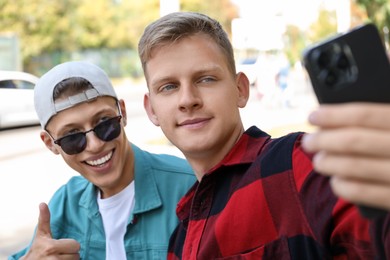 Photo of Happy brothers taking selfie on city street