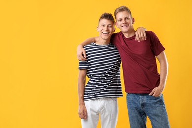 Photo of Portrait of happy brothers on orange background. Space for text