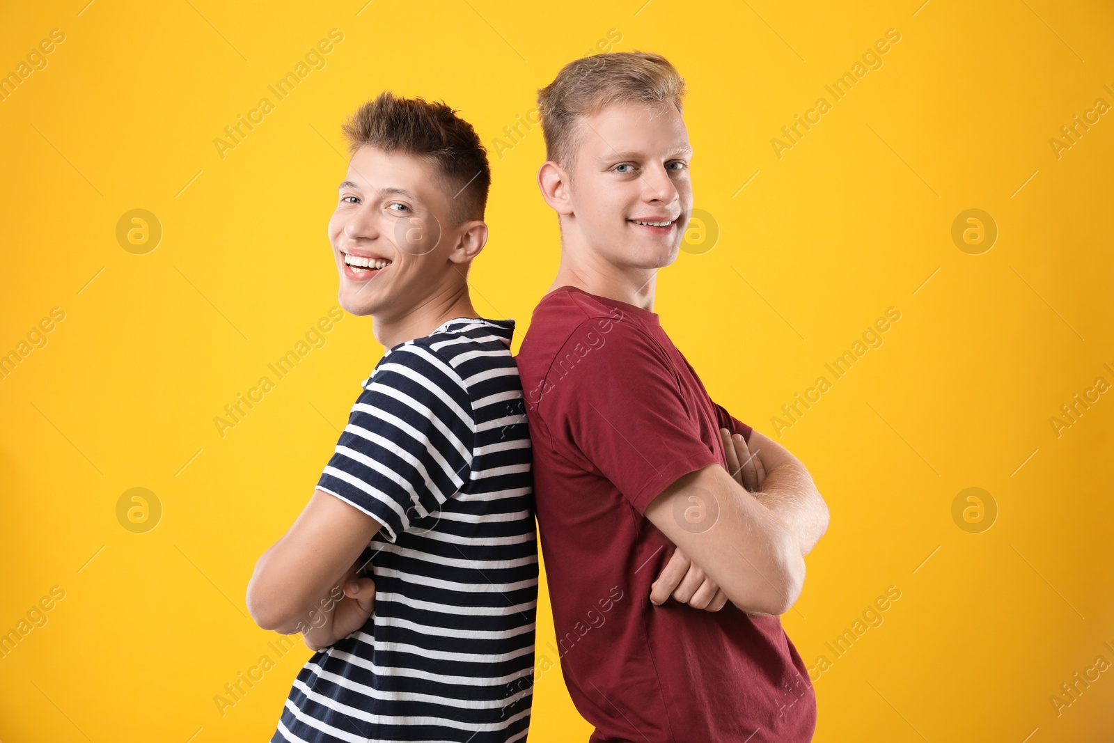 Photo of Portrait of happy brothers with crossed arms on orange background