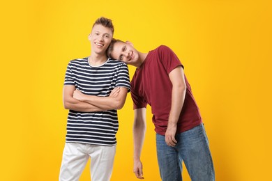 Photo of Portrait of happy brothers on orange background