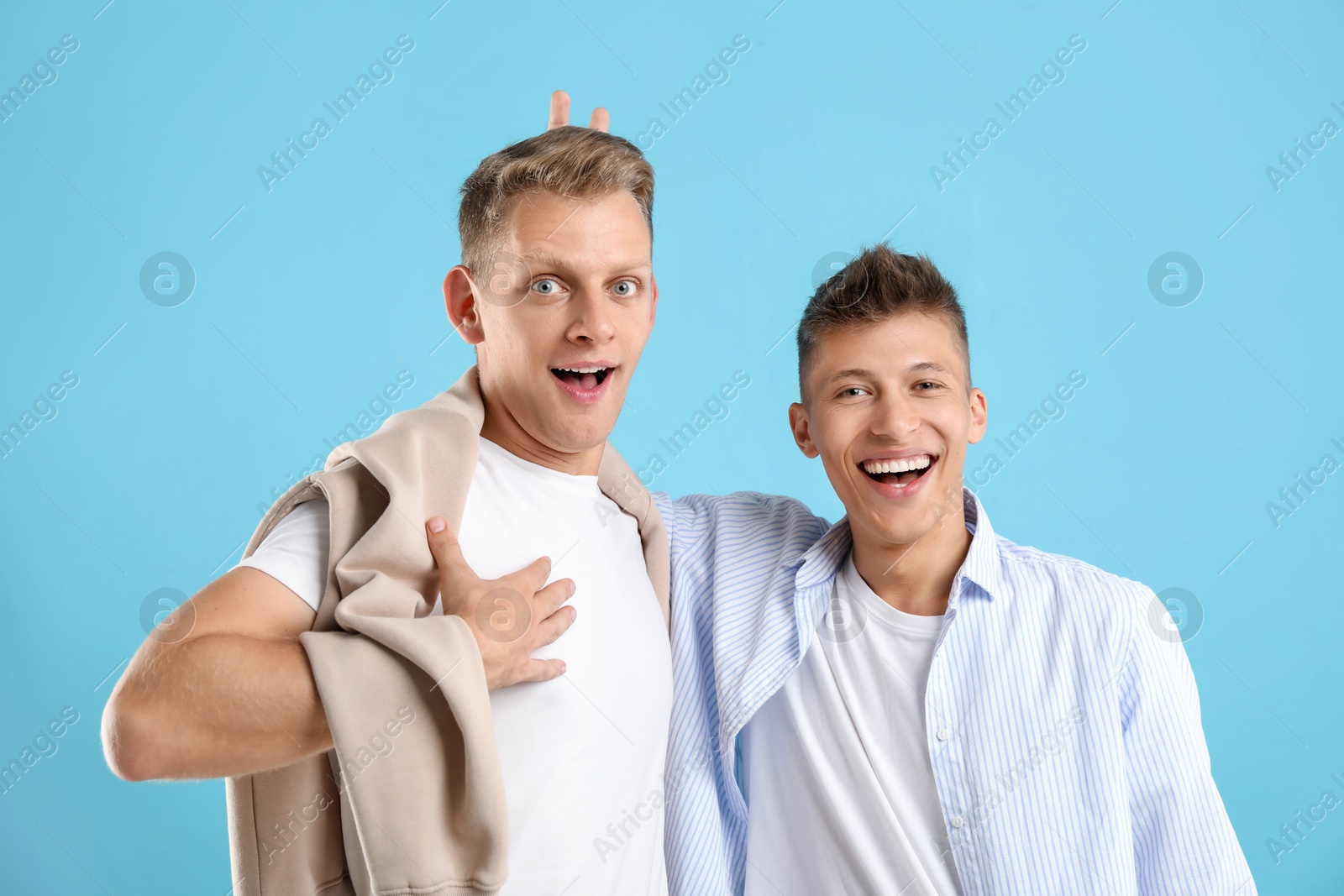 Photo of Portrait of funny brothers on light blue background