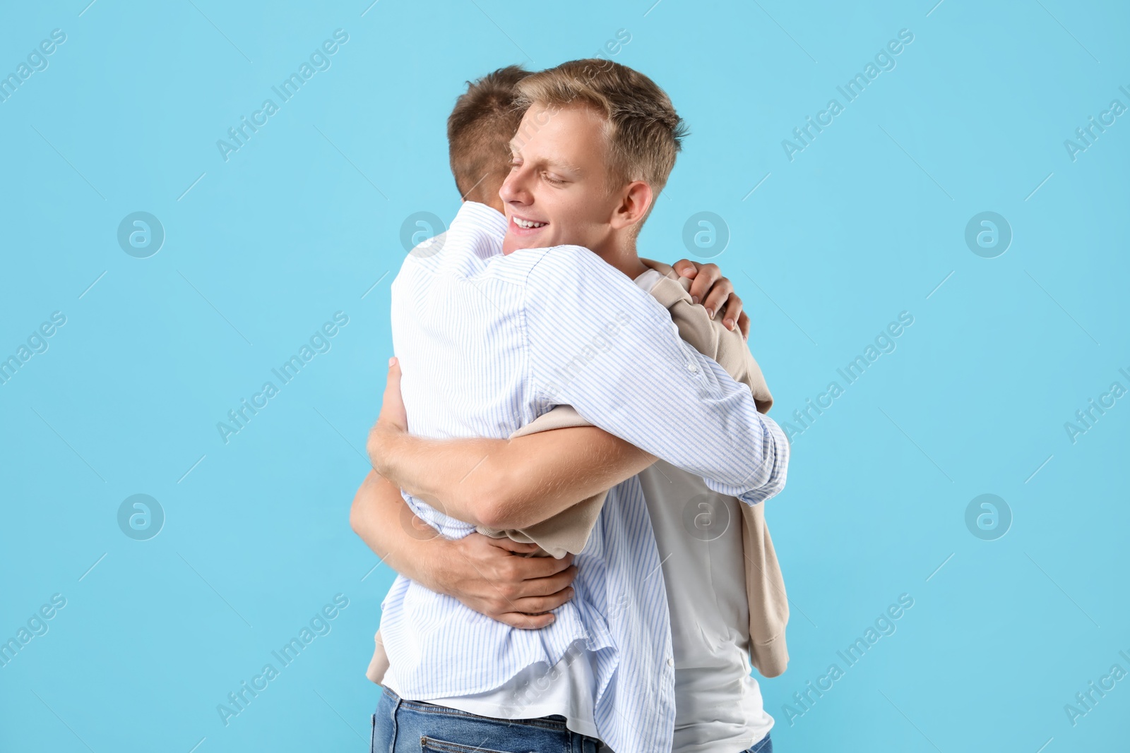 Photo of Two brothers hugging on light blue background