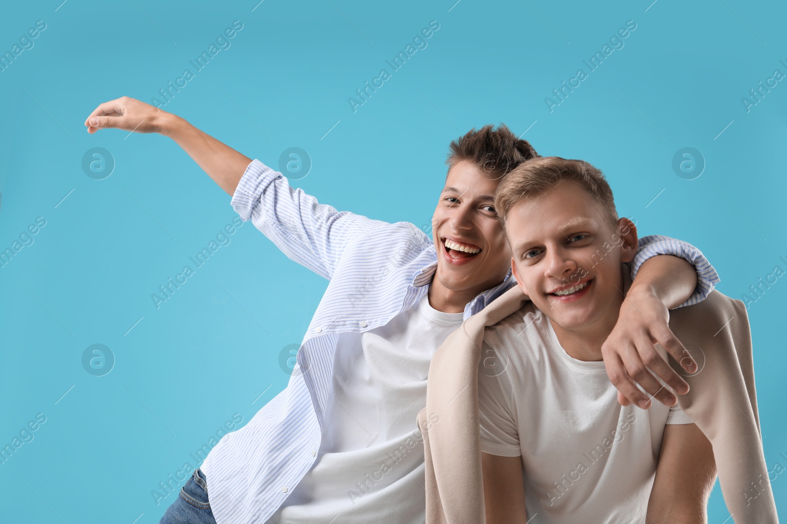 Photo of Portrait of happy brothers on light blue background, low angle view