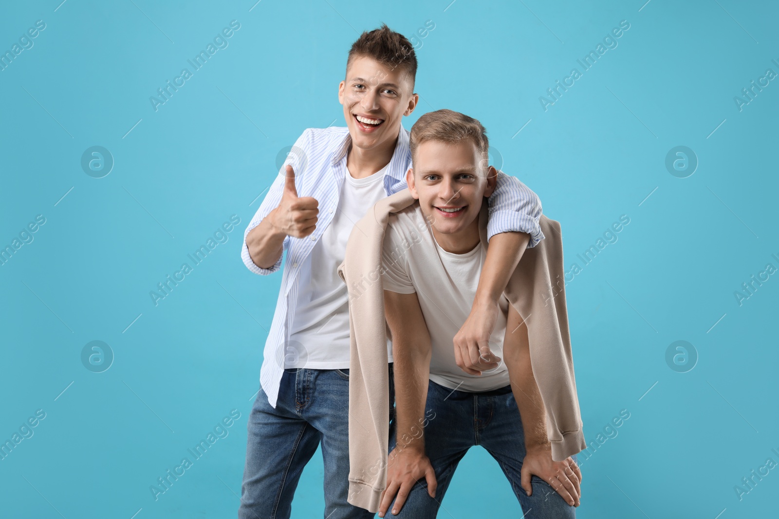 Photo of Portrait of happy brothers on light blue background