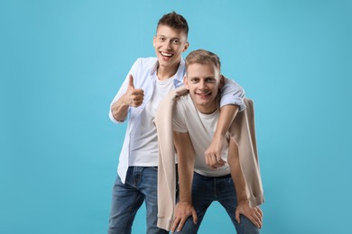 Portrait of happy brothers on light blue background