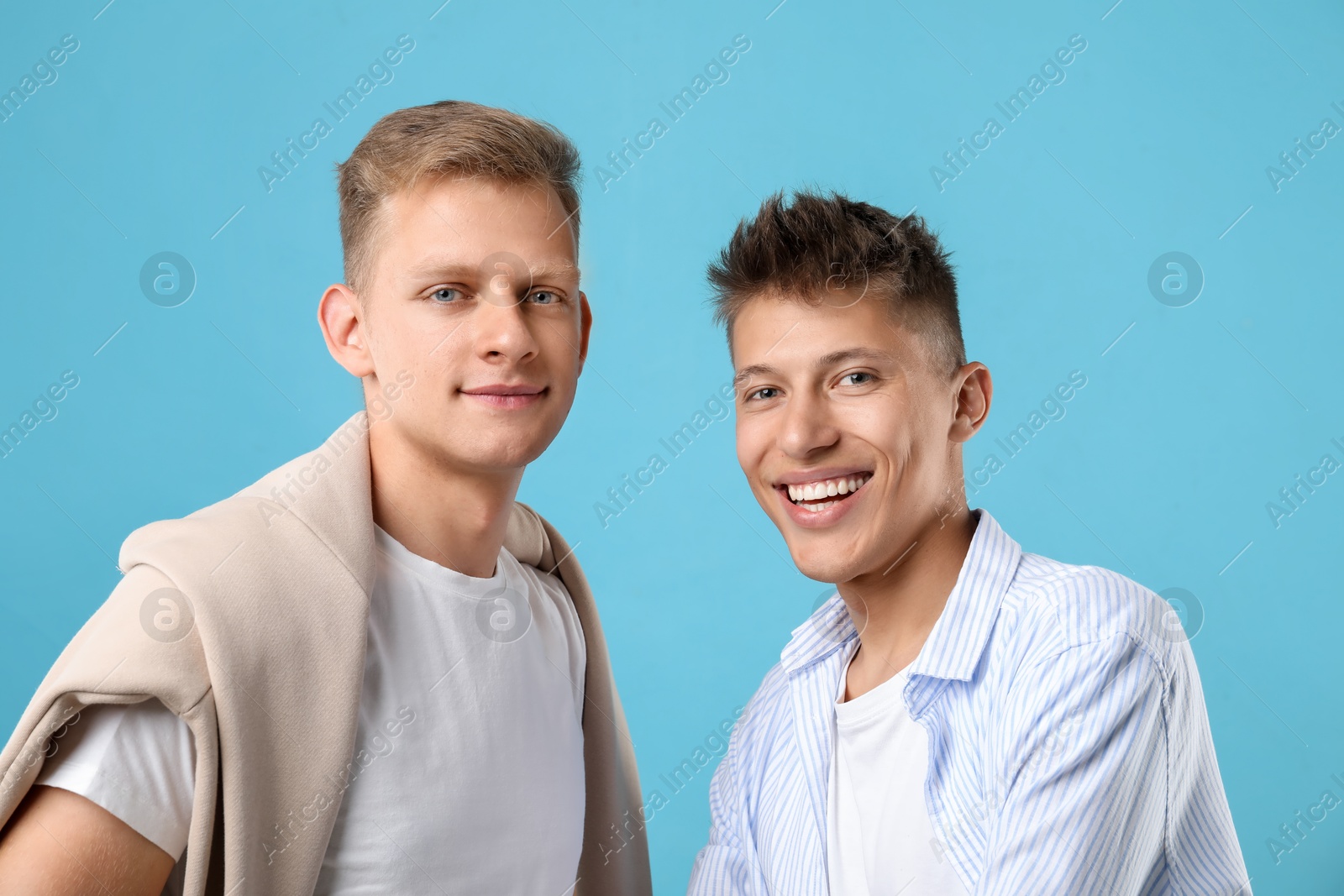 Photo of Portrait of happy brothers on light blue background