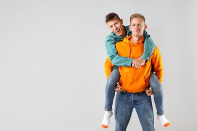 Two happy brothers having fun on light background. Space for text