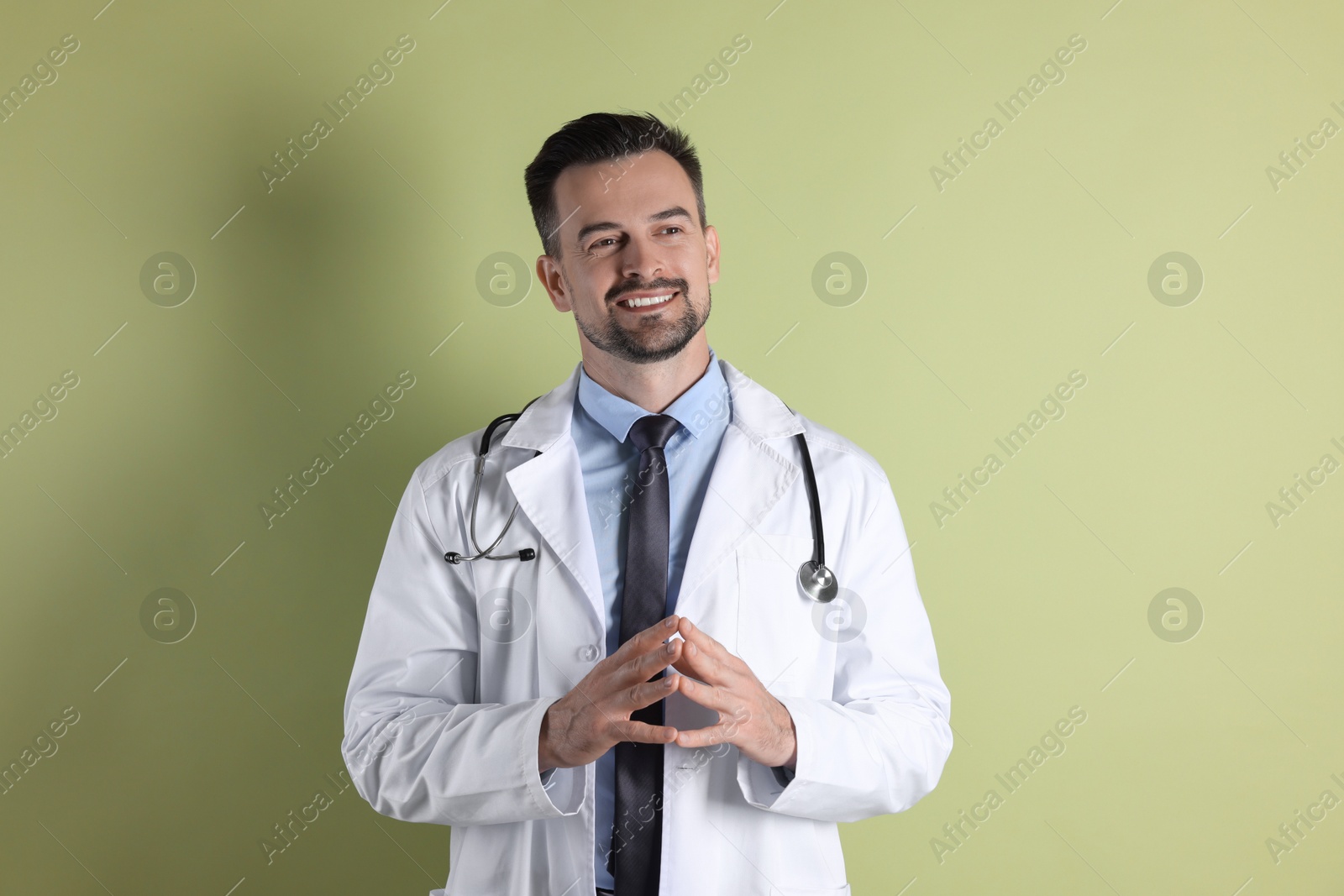 Photo of Smiling doctor with stethoscope on olive background