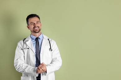 Photo of Smiling doctor with stethoscope on olive background. Space for text