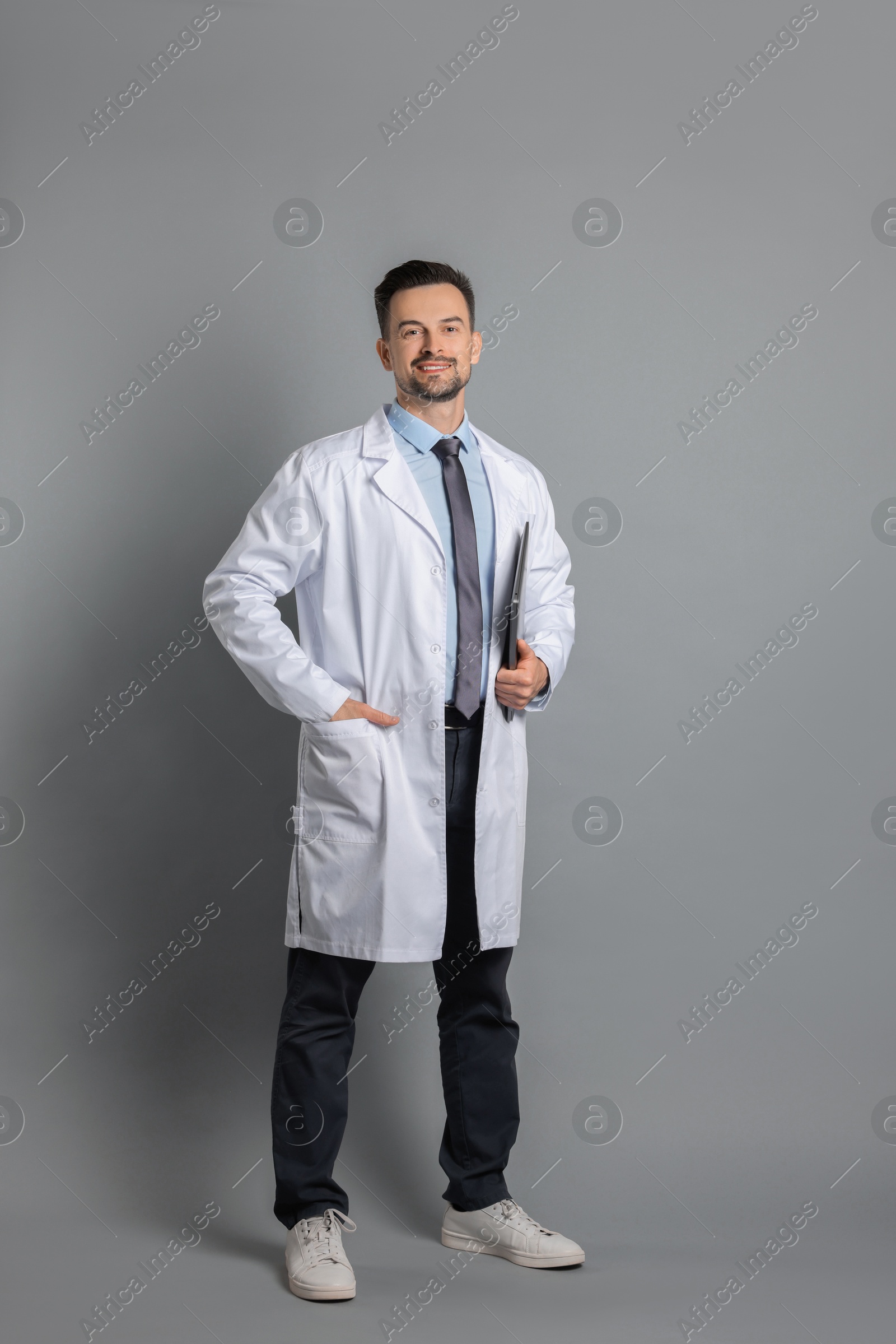 Photo of Smiling doctor with laptop on grey background