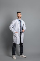 Smiling doctor with laptop on grey background