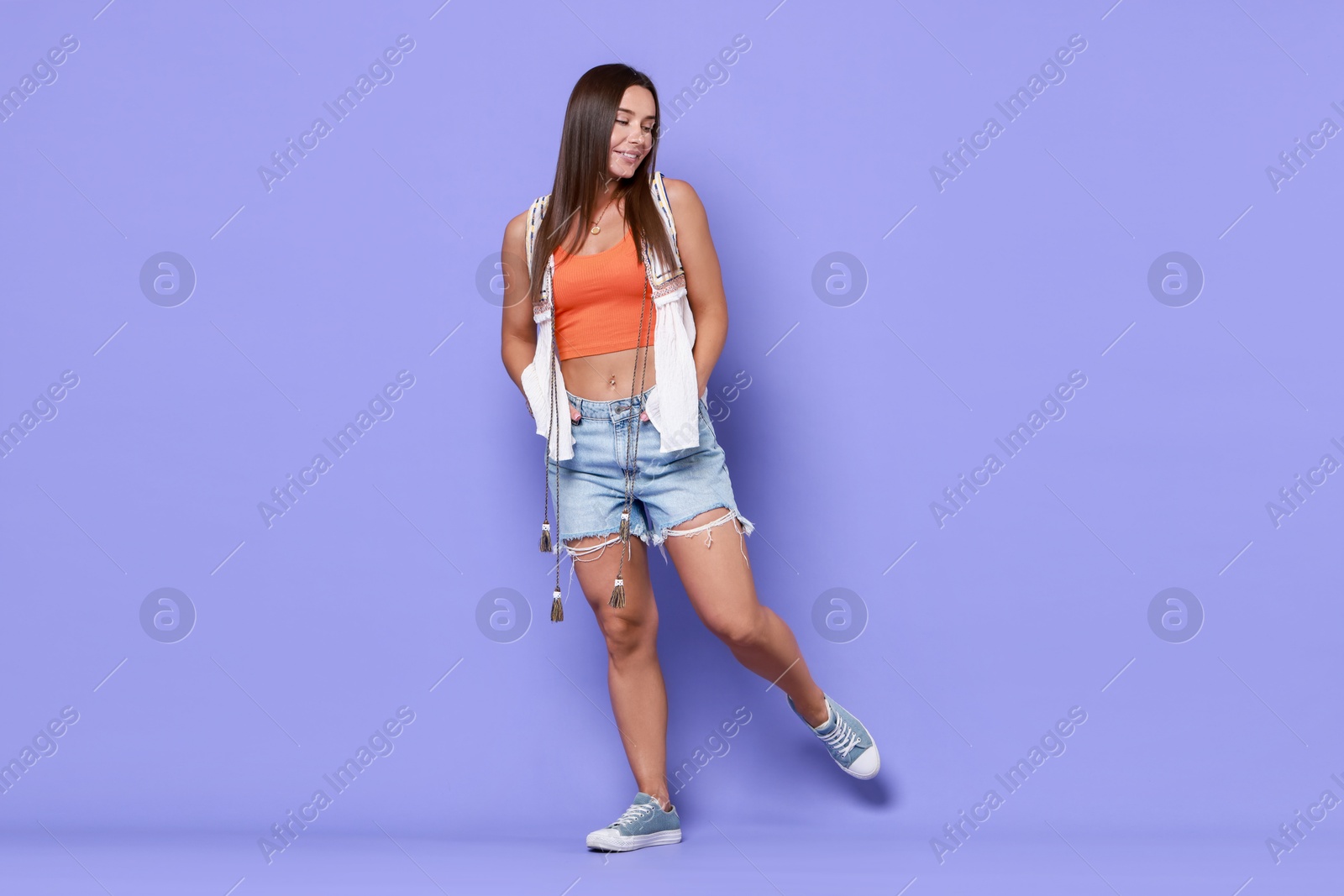 Photo of Beautiful woman wearing stylish denim shorts on violet background