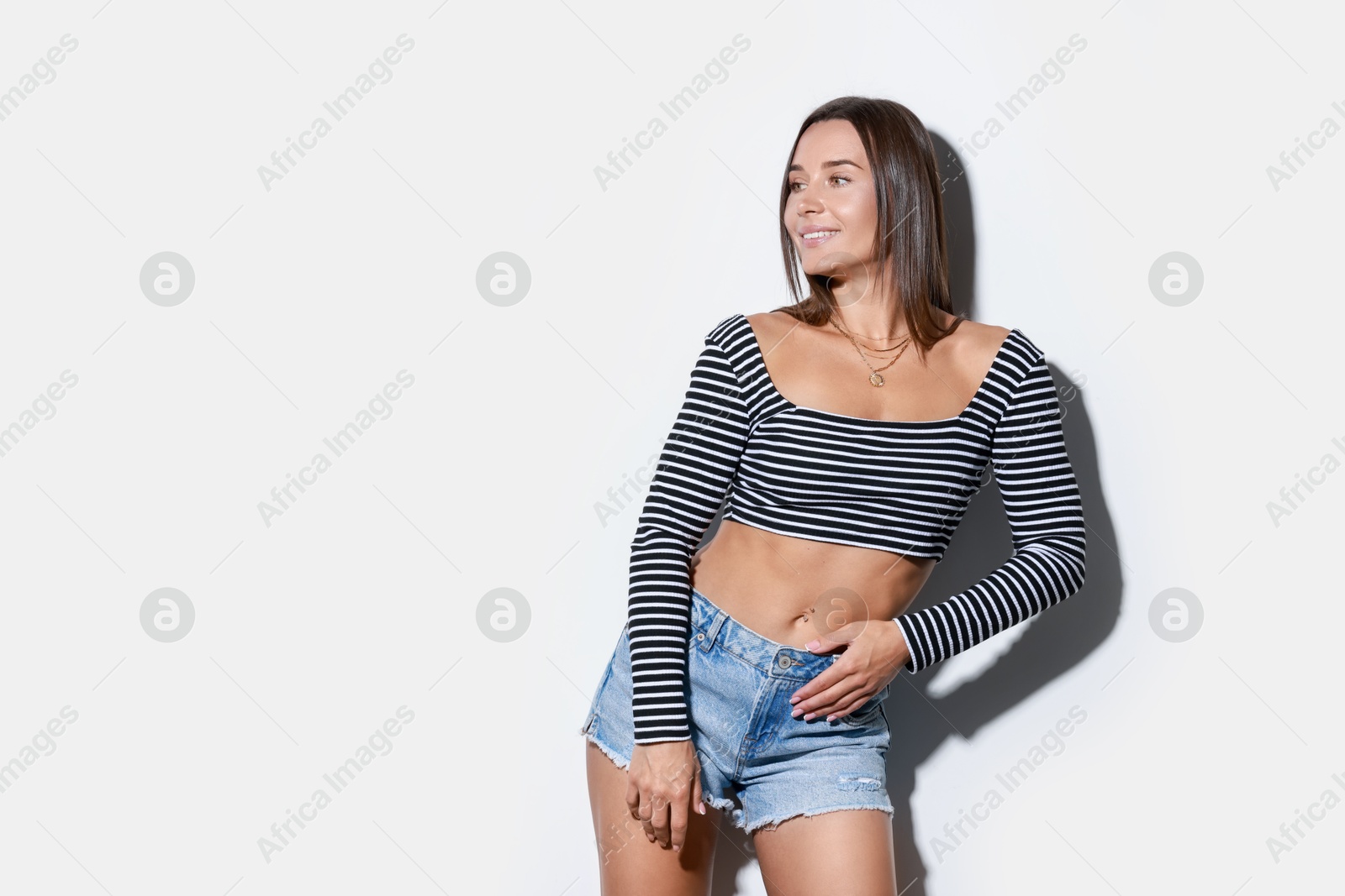 Photo of Beautiful woman wearing stylish denim shorts on white background, space for text