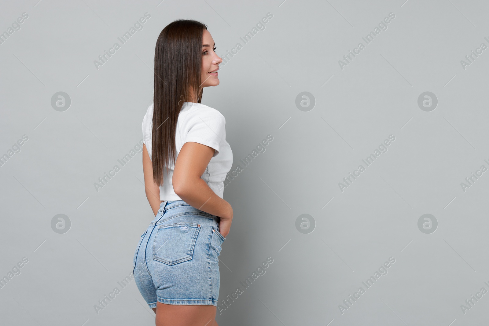 Photo of Beautiful woman wearing stylish denim shorts on gray background, space for text