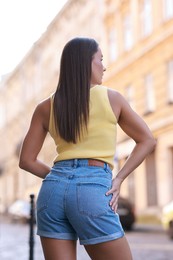 Woman wearing stylish denim shorts outdoors, back view