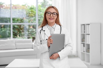 Smiling doctor with stethoscope and laptop in clinic