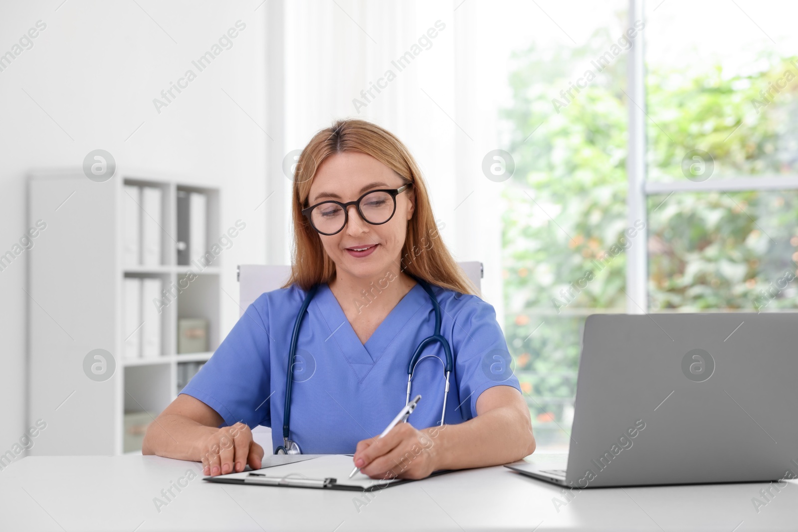 Photo of Doctor with clipboard at table in clinic