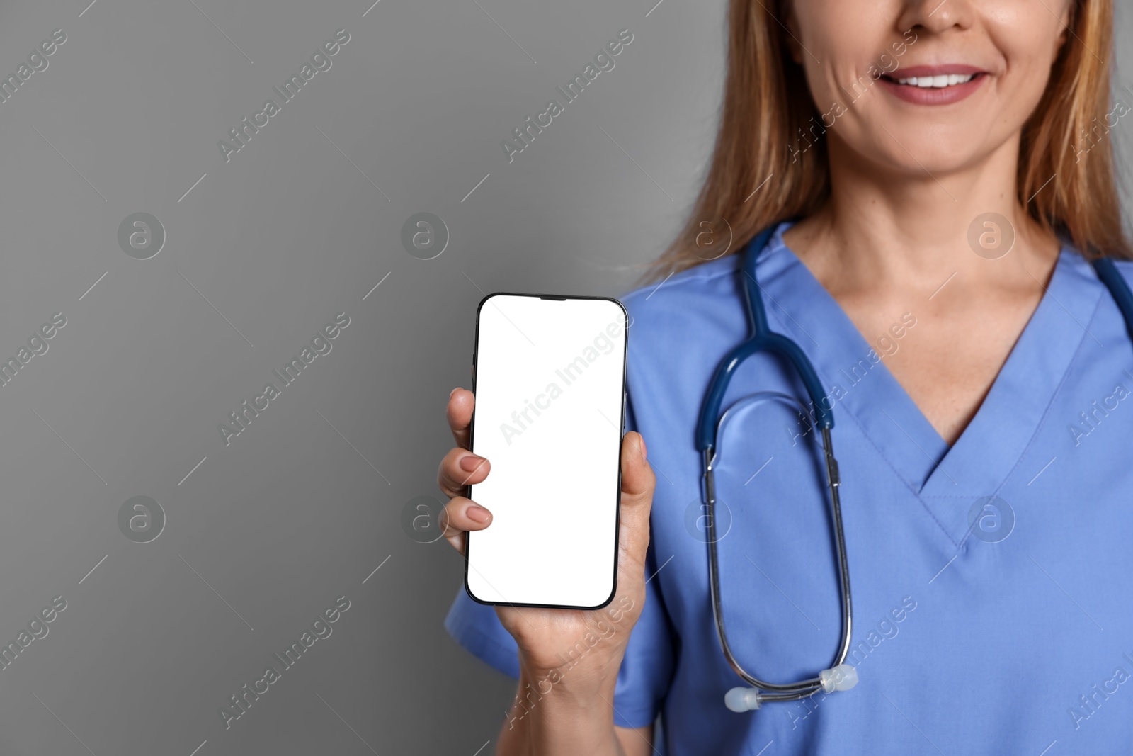 Photo of Doctor showing smartphone with blank screen on gray background, closeup. Mockup for design