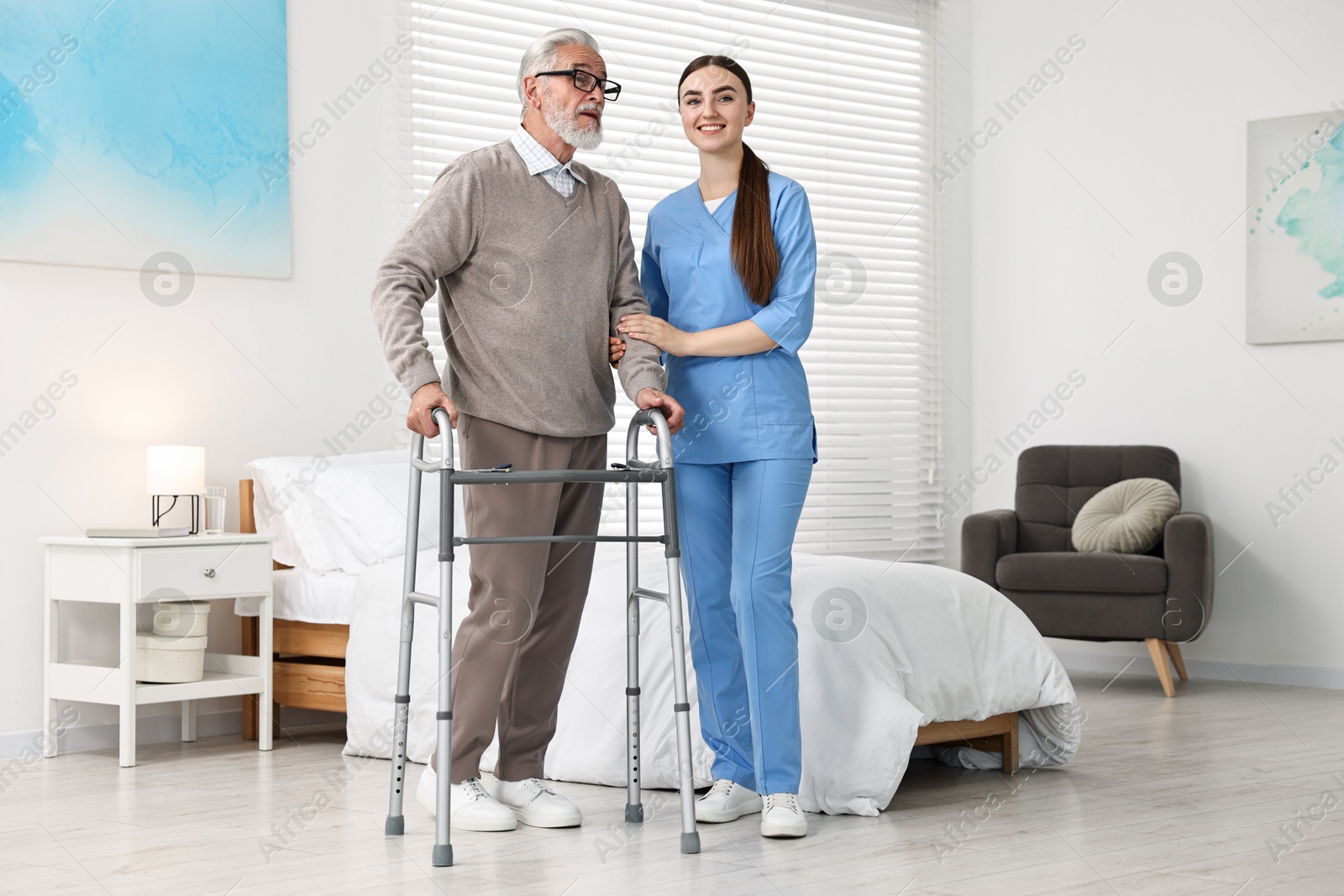 Photo of Nurse helping senior man with walking frame in clinic