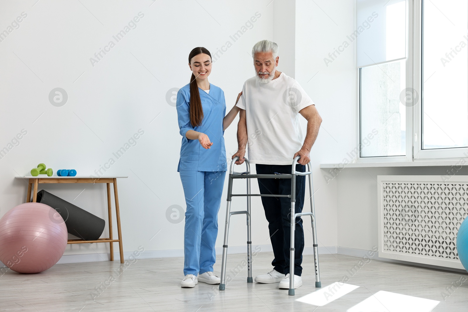 Photo of Nurse helping senior man with walking frame in clinic