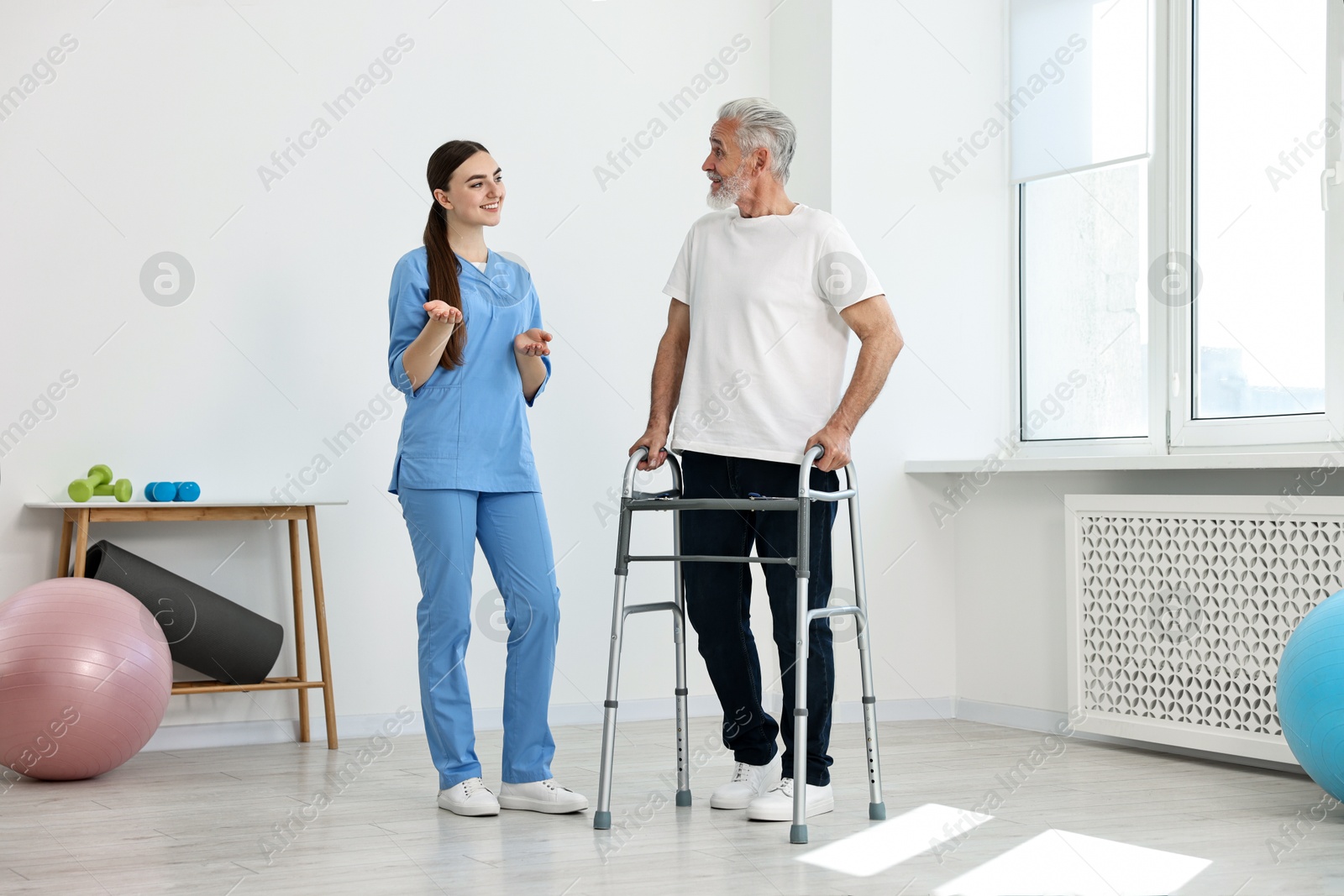 Photo of Nurse talking to senior man with walking frame in clinic