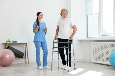 Nurse talking to senior man with walking frame in clinic