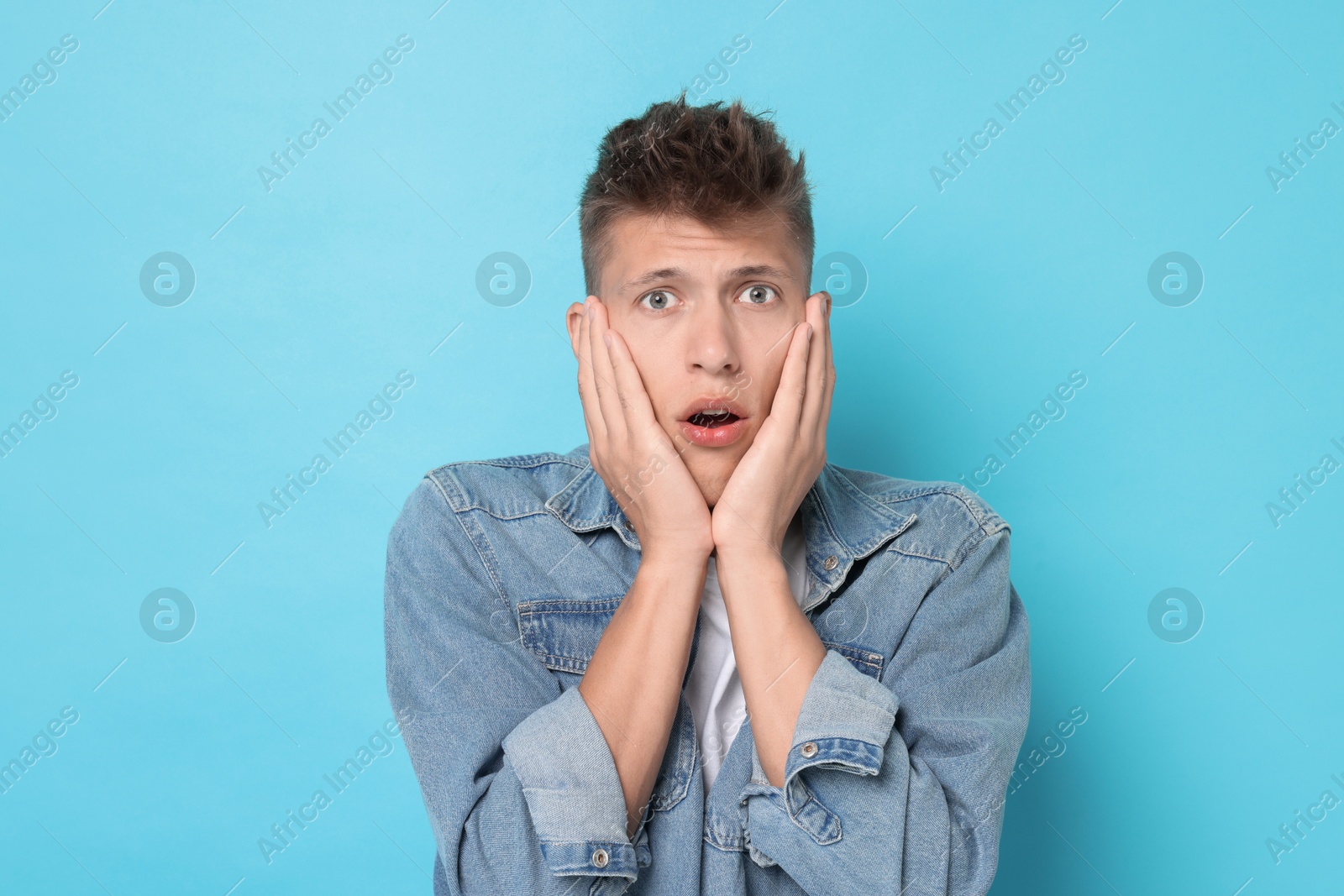 Photo of Portrait of scared young man on light blue background