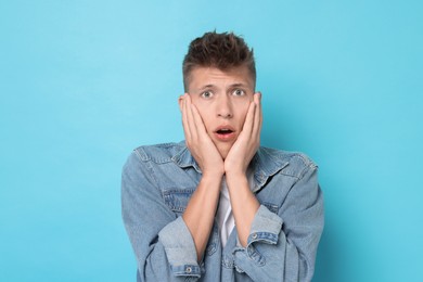 Portrait of scared young man on light blue background