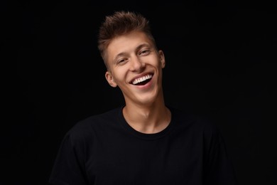 Photo of Portrait of happy young man on black background