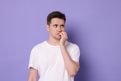 Portrait of scared young man on violet background