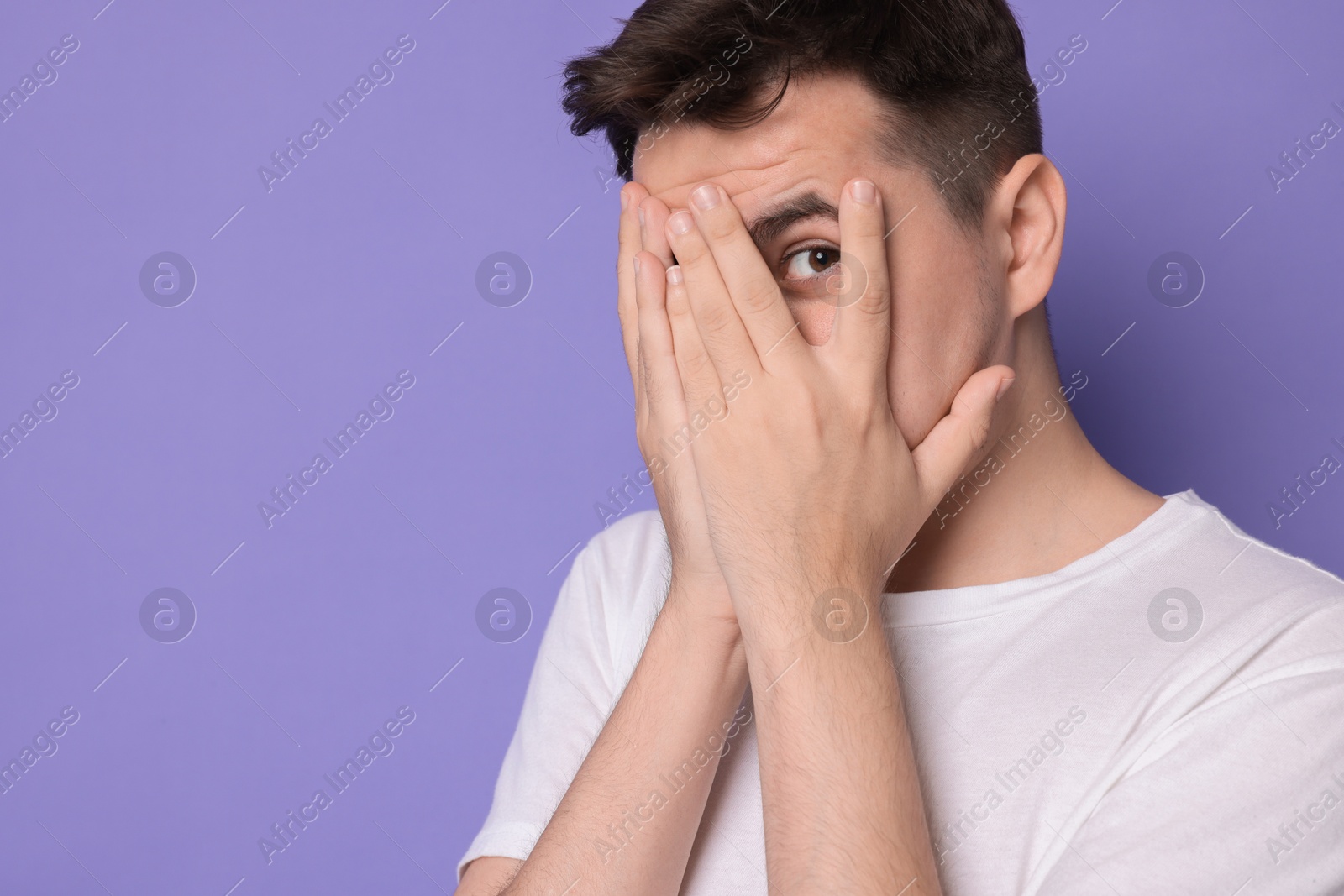 Photo of Portrait of scared young man on violet background, space for text