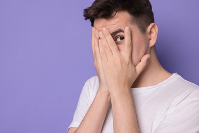 Portrait of scared young man on violet background, space for text