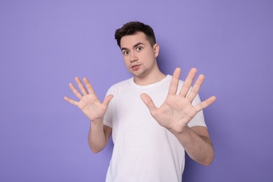 Portrait of scared young man on violet background