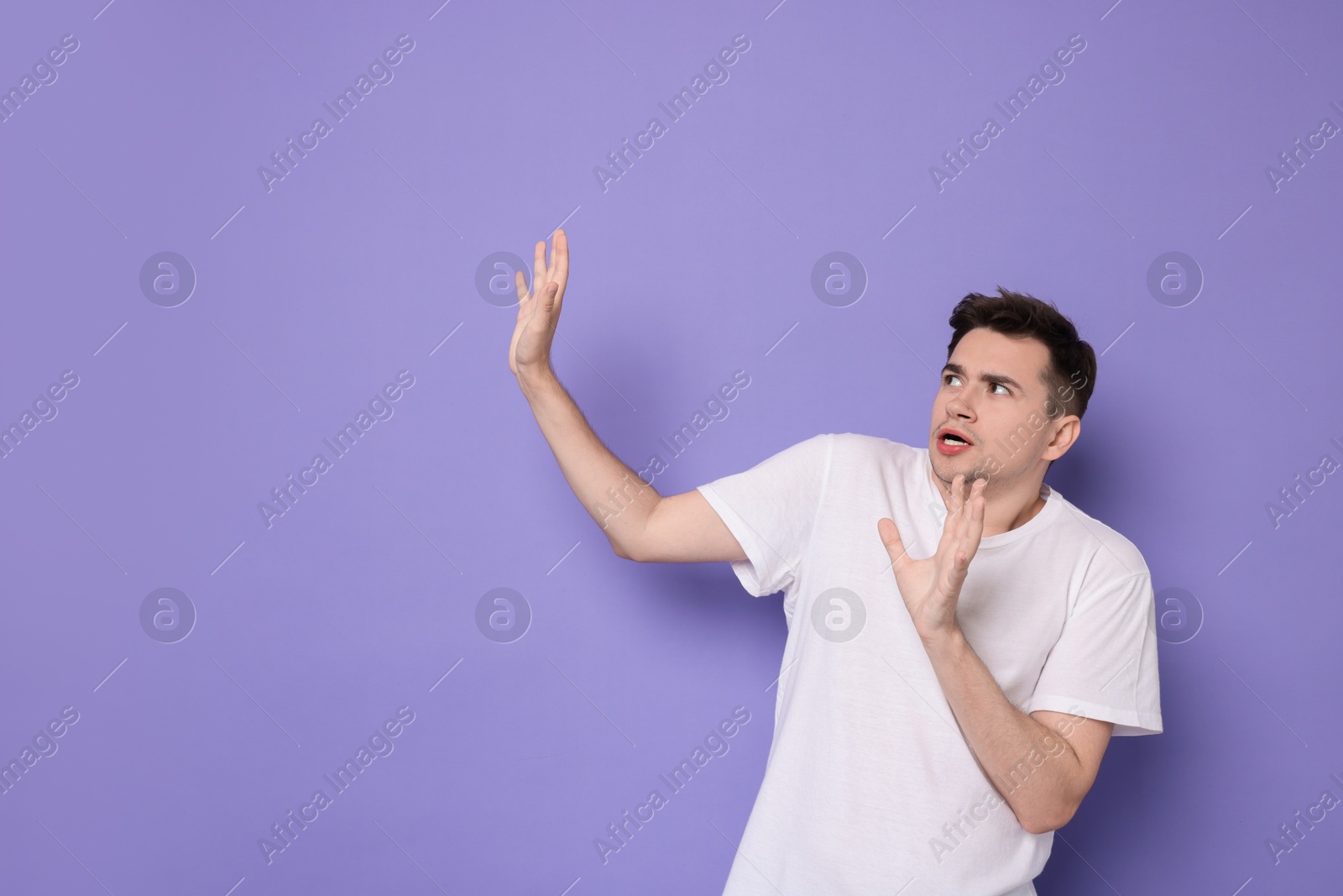 Photo of Portrait of scared young man on violet background, space for text