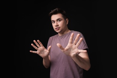 Portrait of scared young man on black background