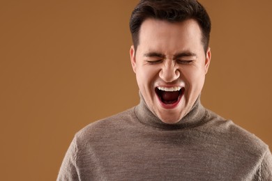 Portrait of scared young man on brown background, space for text