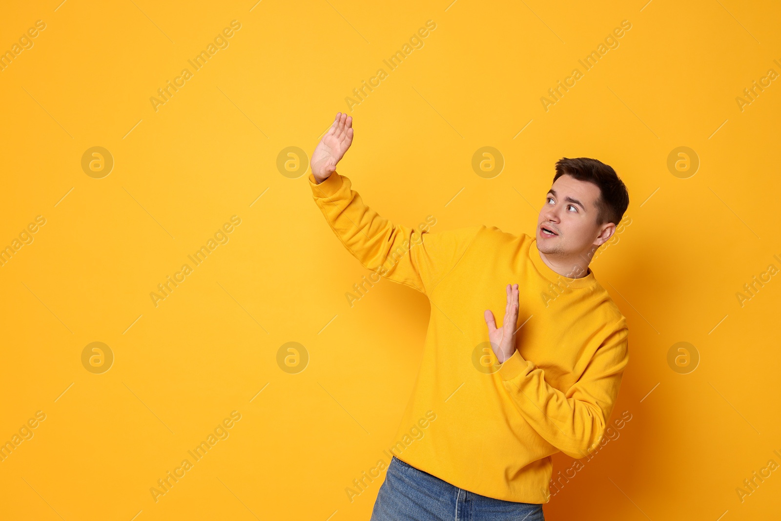 Photo of Portrait of scared young man on orange background, space for text