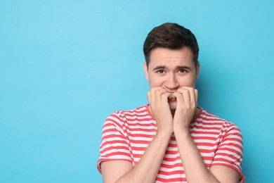 Photo of Portrait of scared young man on light blue background, space for text