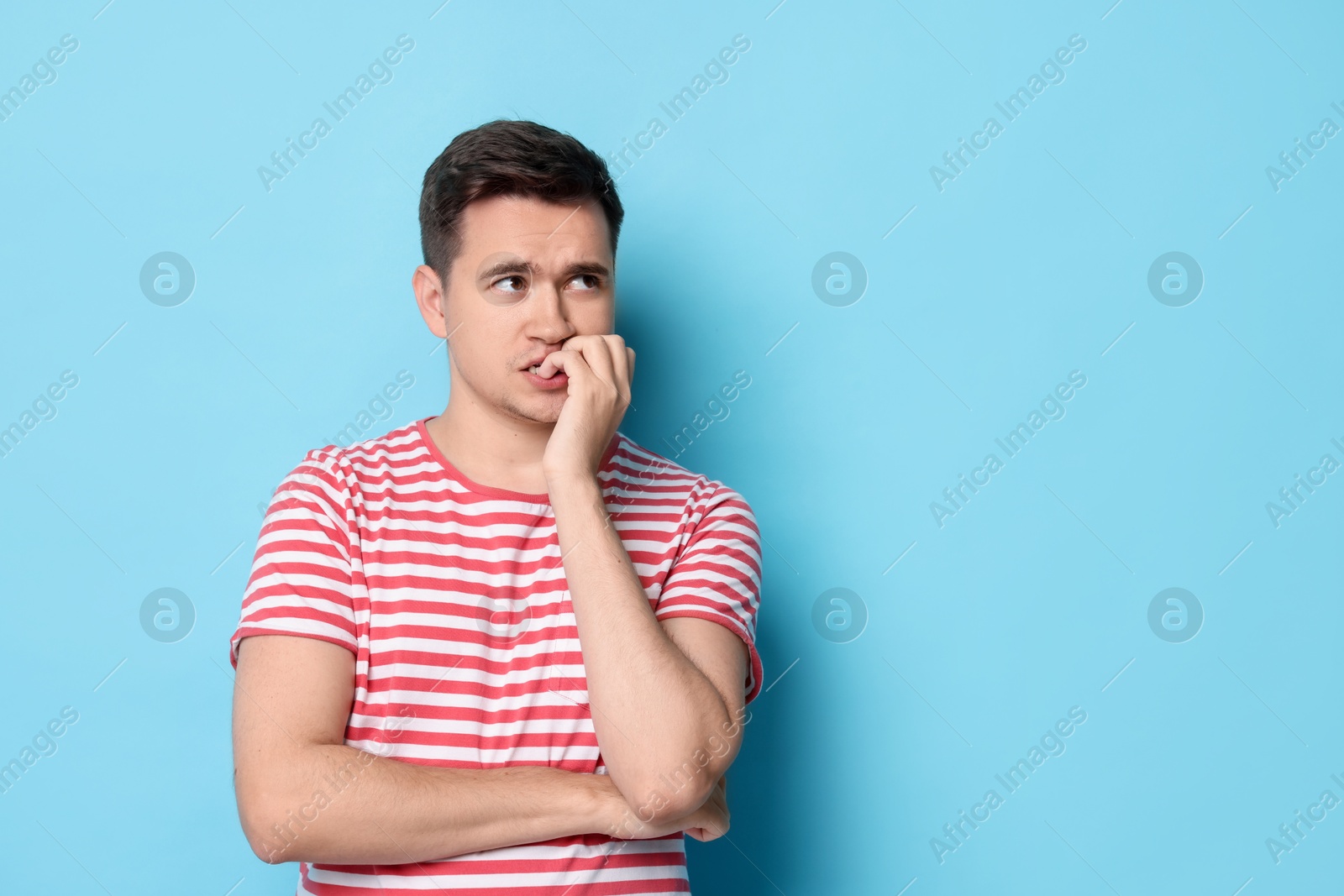 Photo of Portrait of scared young man on light blue background, space for text