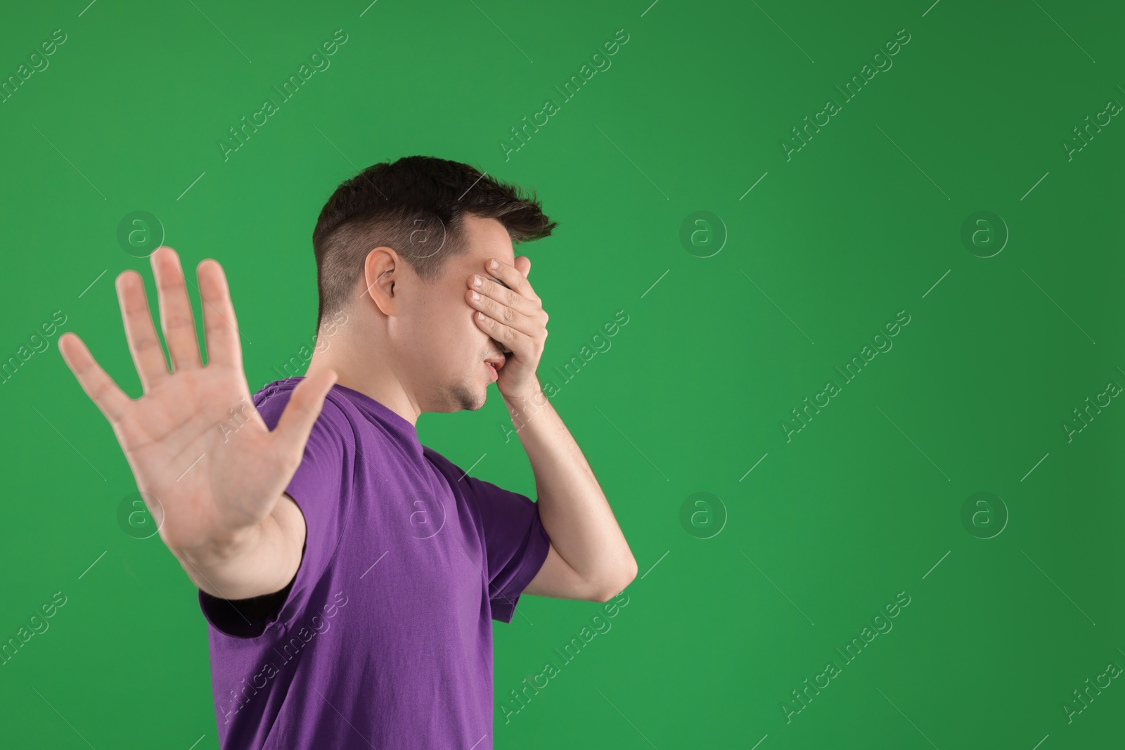 Photo of Portrait of scared young man on green background, space for text