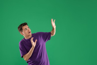 Portrait of scared young man on green background, space for text