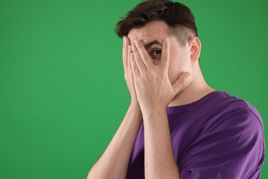 Portrait of scared young man on green background, space for text