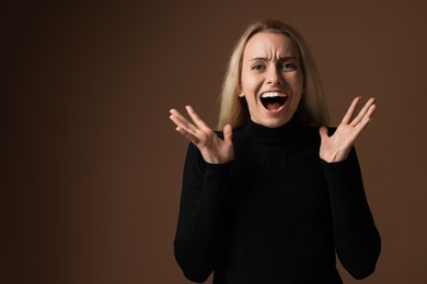 Portrait of scared woman on brown background, space for text