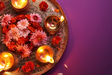 Photo of Diwali celebration. Diya lamps and beautiful flowers on color background, top view. Space for text