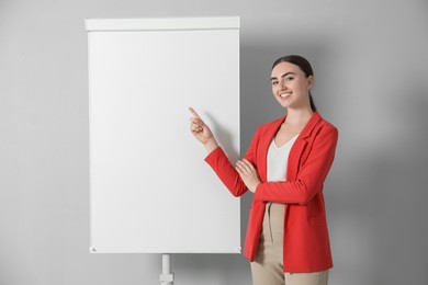 Happy woman near flip chart on grey background. Mockup for design